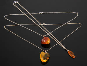 Tre vedhæng med kæde af sølv, prydet med sleben ravstykke. 3