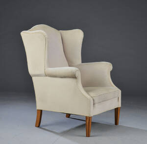 Øreklapstol ben ben af egetræ, overpolstret med grå-hvid betræk.