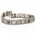 Et diamantarmbånd af 14 kt. hvidguld prydet med talrige diamanter med ældre slibning samt blå sten. L. ca. 17,5 cm. Ca. 1930-40.
