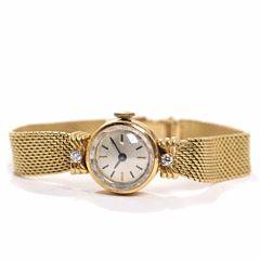 Damearmbåndsur af 18 kt. guld, prydet med to brillantslebne diamanter. Integreret lænke. L. 15. Kassediam. 15 mm. Ca. 1960.