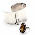 Smykkesæt af sterlingsølv bestående af armring samt ring prydet med cabochonslebet rav. Str. 60. Indvendig diam. ca. 6,4 cm.B. 3, 8 cm. 2