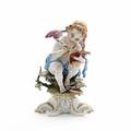 Figur af porcelæn i form af putto med pen og bog dekoreret i guld og farver, Cappo di Montes mærke. Ca. 1900. H. 23 cm.