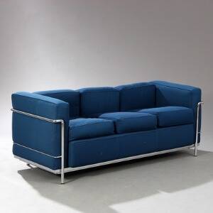 Le Corbusier LC 2. Fritstående tre-personers sofa med stel af stål. Sæde, ryg, løse hynder og armlæn betrukket med blåt stof.