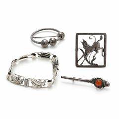 Smykkesamling af sølv bestående af armbånd og tre brocher, én prydet med poleret rav. L. ca. 5,4 og 18 cm. Diam. ca. 4,2 og 5 cm. Æske medfølger. 4