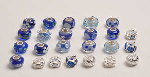 24 Charlotte Borgen charms i sterling sølv, nogle med glas i blå nuancer