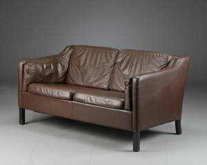 Sofa med stel af sortlakeret træ, betræk og hynder monteret med brunt skind. L. 140 cm.