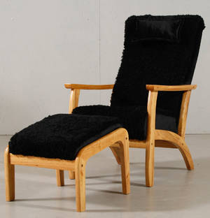 Fåtölj och fotpall klädda med svart fårskinn