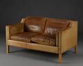 Stouby sofa med stel af bøgetræ, betræk og hynder med lyst skind.