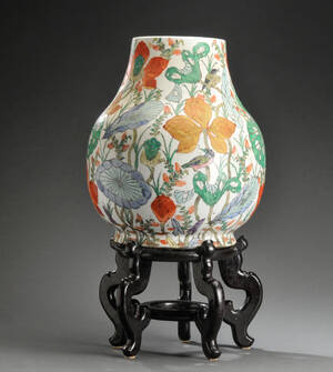 Kinesisk vase af porcelæn dekoreret med blomster og bladværk, på stand af træ.
